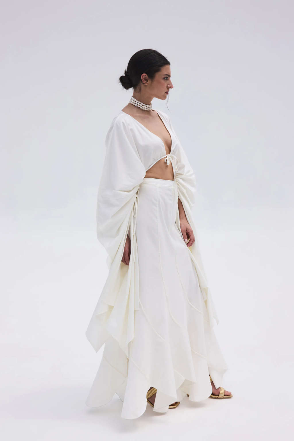 Chica con un look blanco, collar de perlas y sandalias