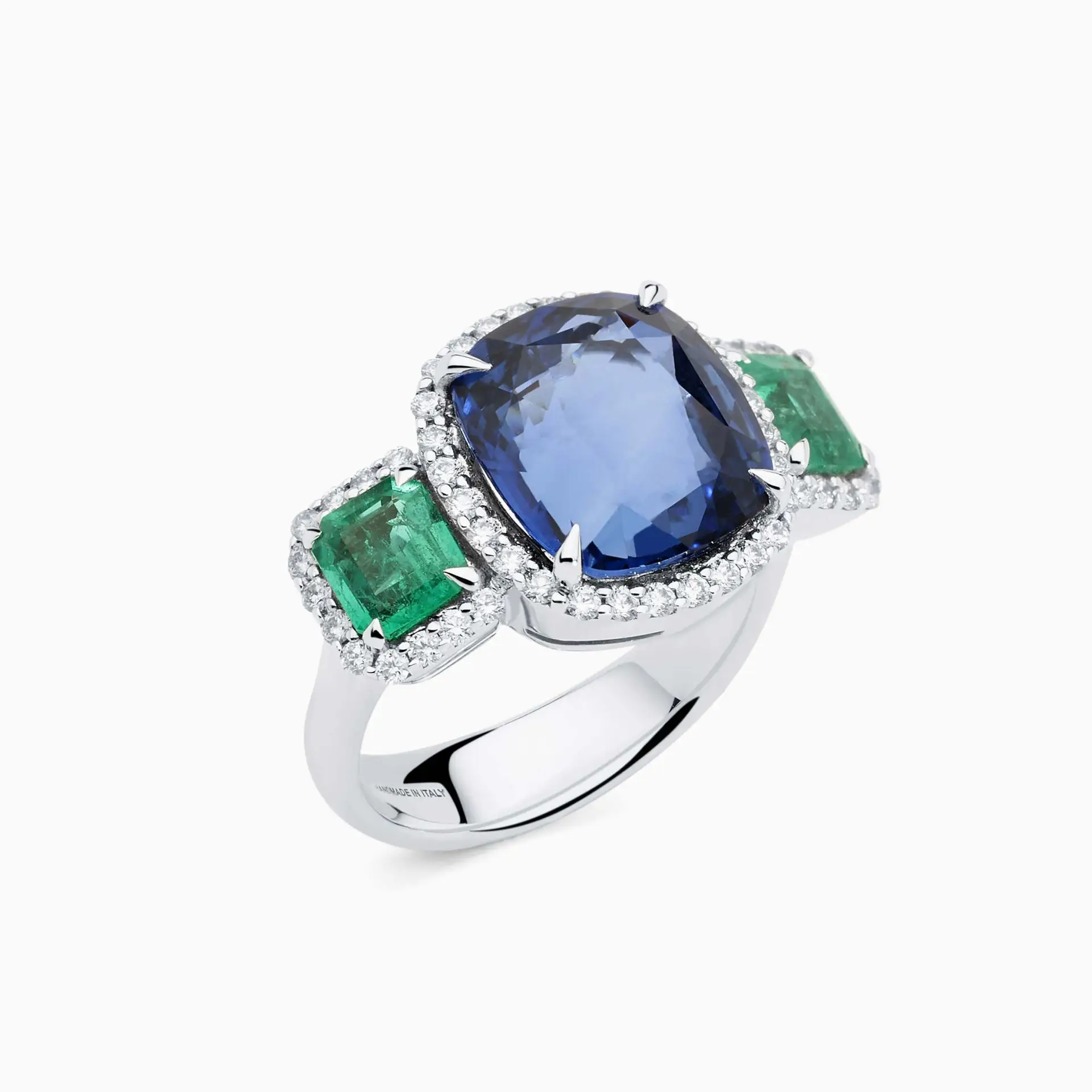 Anillo de oro blanco con zafiro central azul, esmeraldas laterales y corona de diamantes