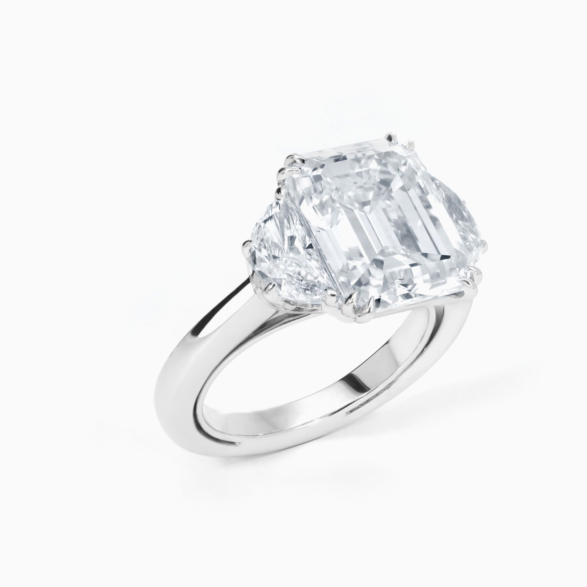 Anillo tresillo de oro blanco con diamante central talla esmeralda y diamantes laterales media luna