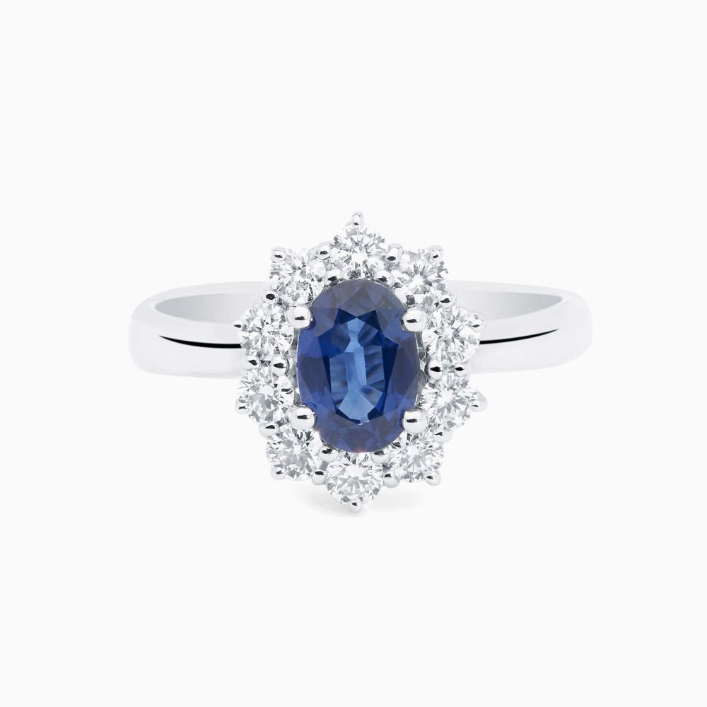 Anillo solitario de oro blanco con zafiro azul central talla oval y orla de diamantes